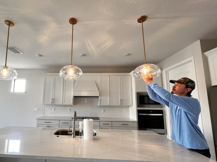 Electrician installing a glass pendant light in a kitchen